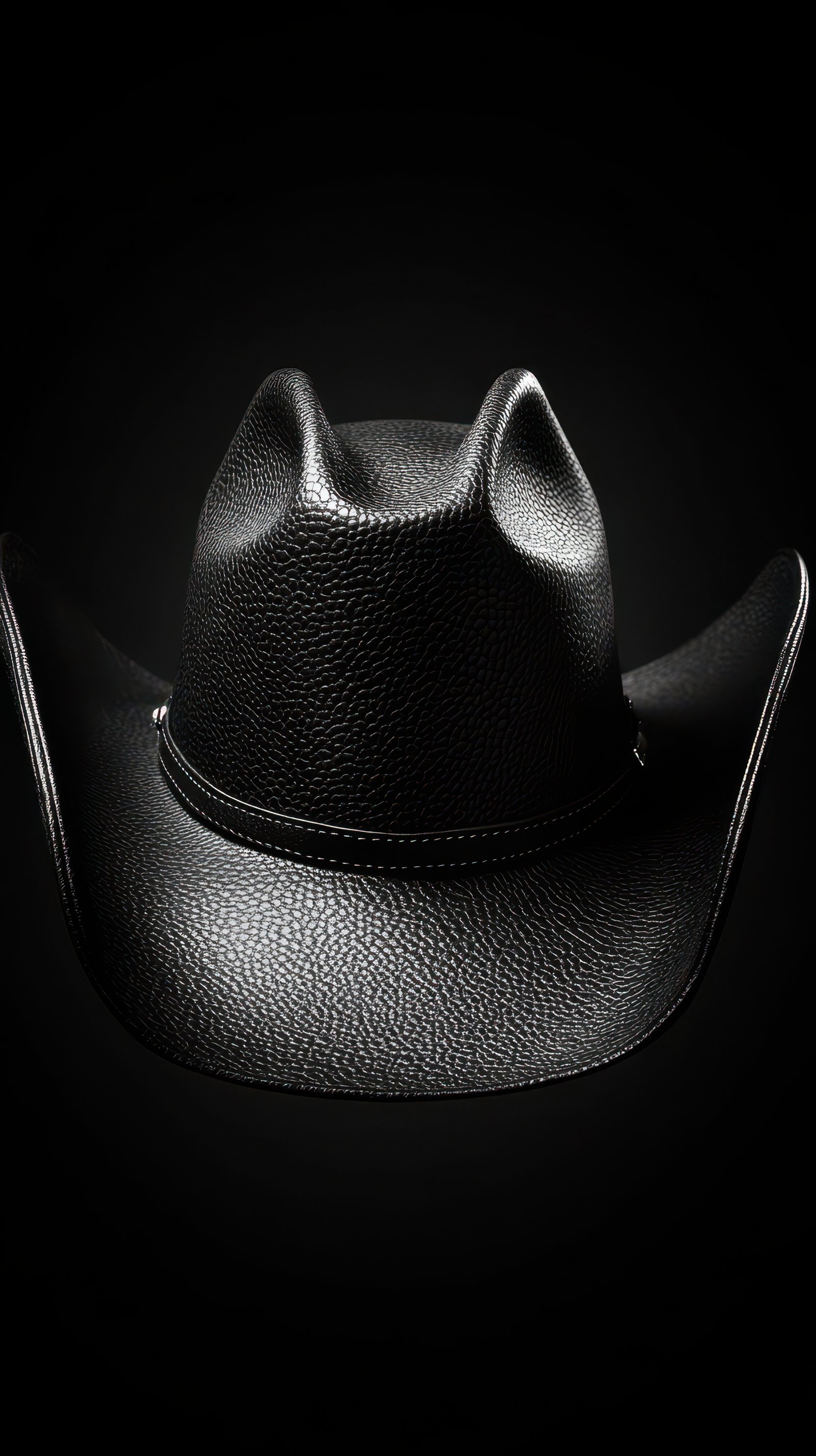 Black leather cowboy hat displayed against a contrasting dark background emphasizing its shape and texture